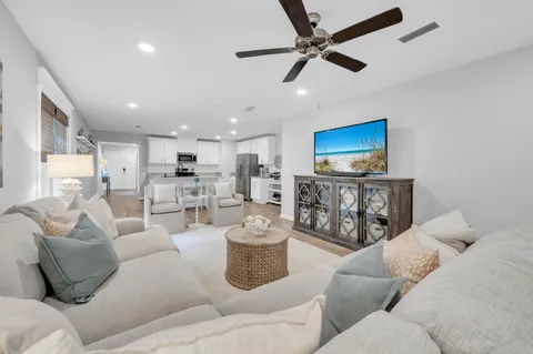 a living room with furniture a ceiling fan and a flat screen tv