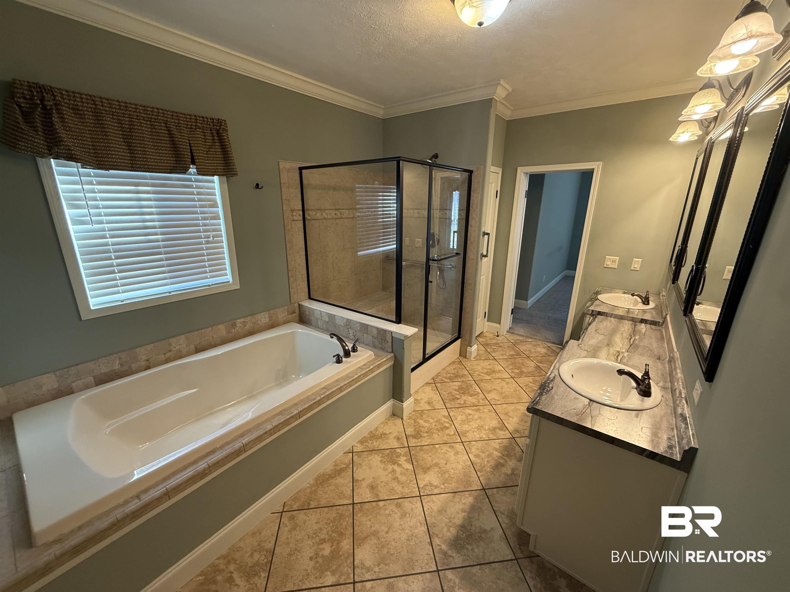 1274 Caney Loop Lillian, AL 36549 - Photo 16 of 19 Bathroom featuring double vanity, crown molding, light tile patterned floors, a bath, and a shower stall