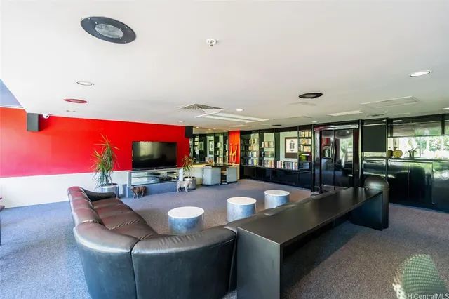 a living room with couches a flat screen tv and a large window with kitchen view