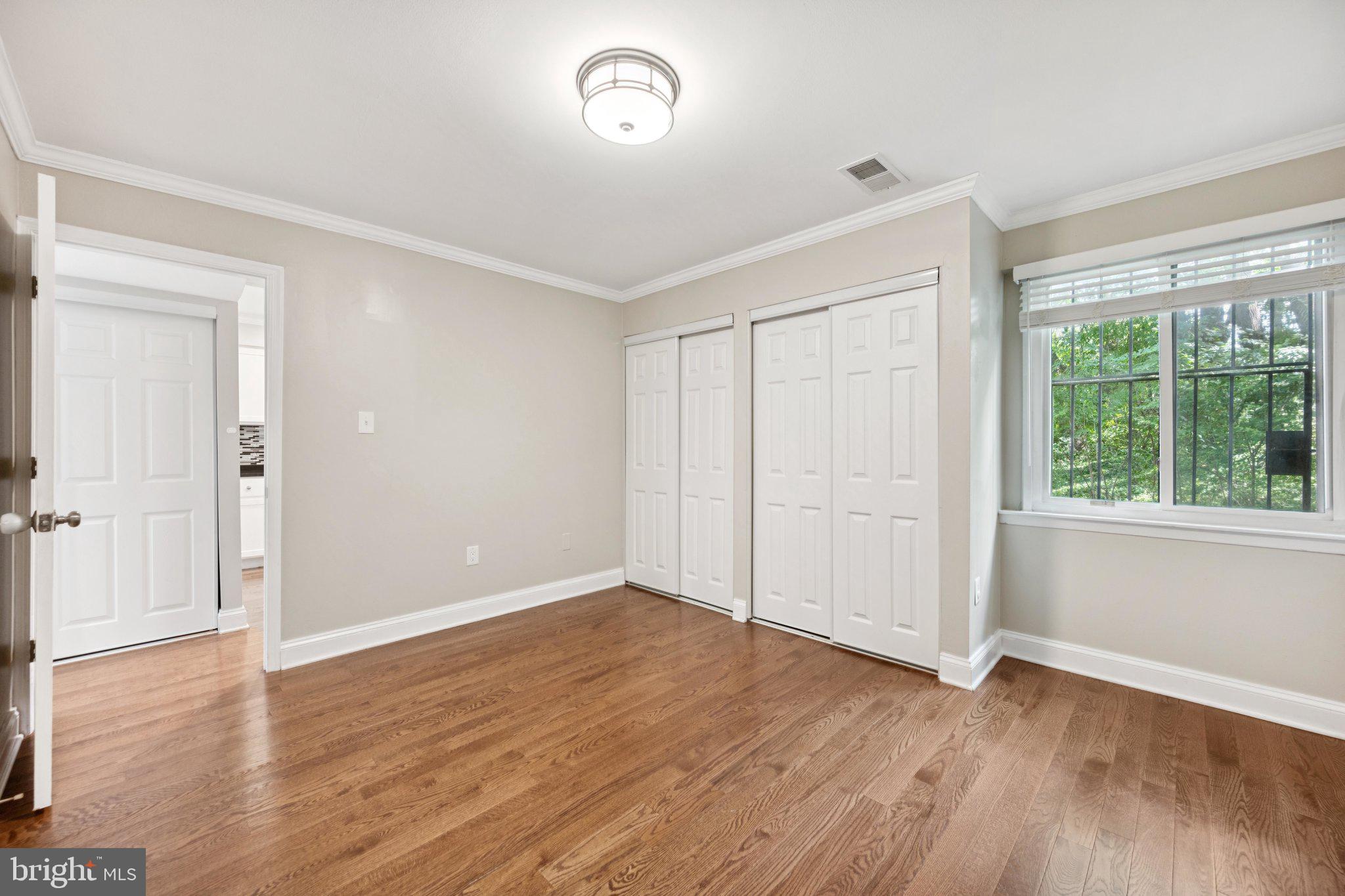 2016 Coleridge Drive, Unit 24102 Silver Spring, MD 20902 - Photo 13 of 19 a view of an empty room with wooden floor and a window