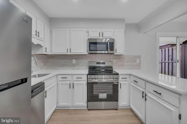 a kitchen with white cabinets and stainless steel appliances