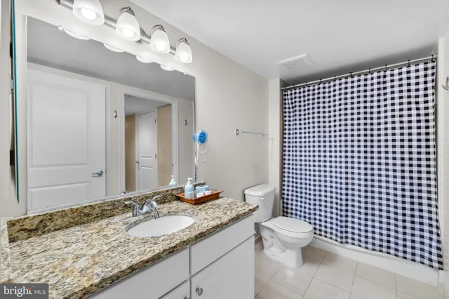 a bathroom with a granite countertop sink a toilet and a mirror