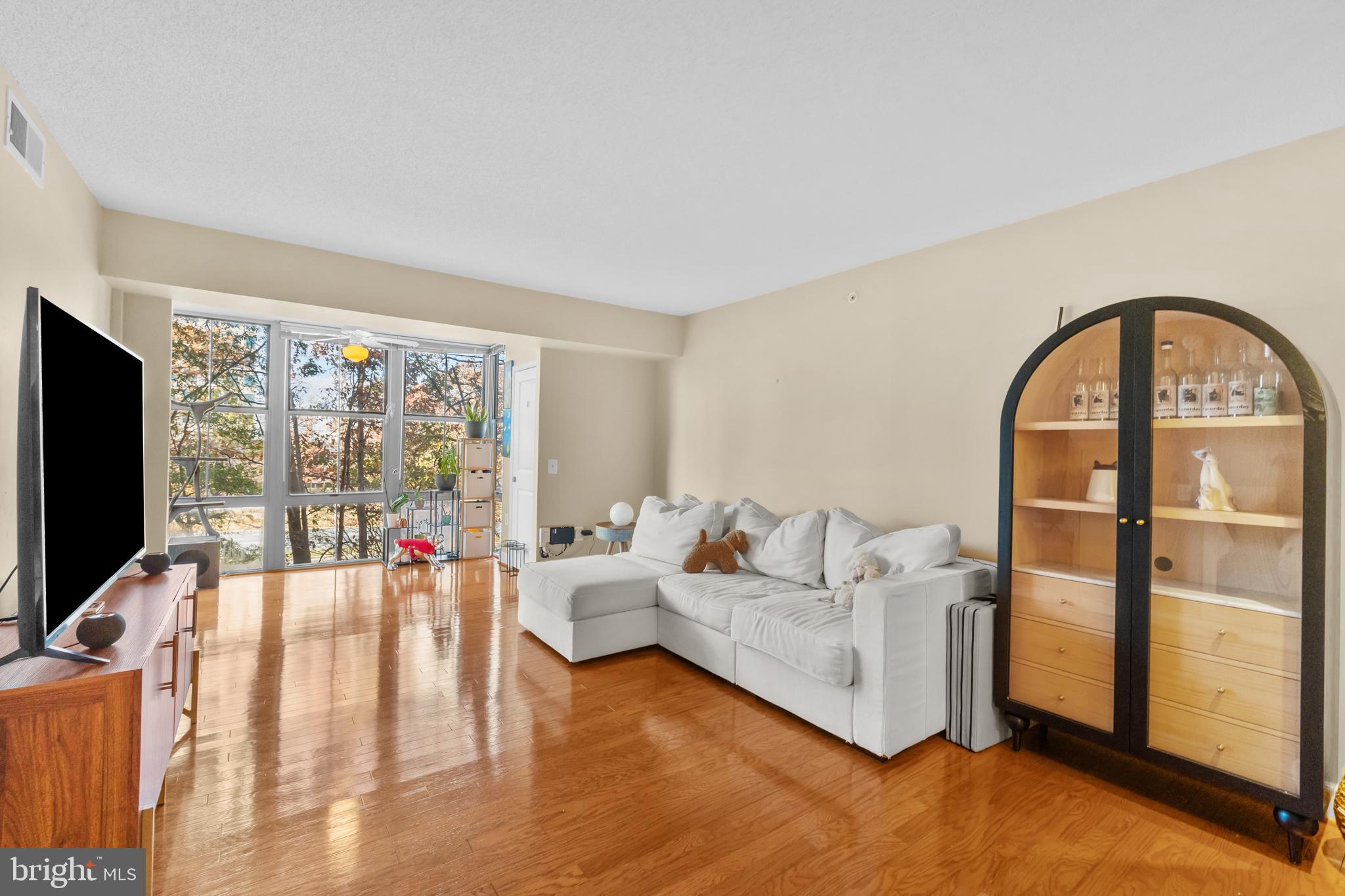 11800 Sunset Hills Road, Unit 409 Reston, VA 20190 - Photo 4 of 35 a living room with furniture a flat screen tv and a floor to ceiling window