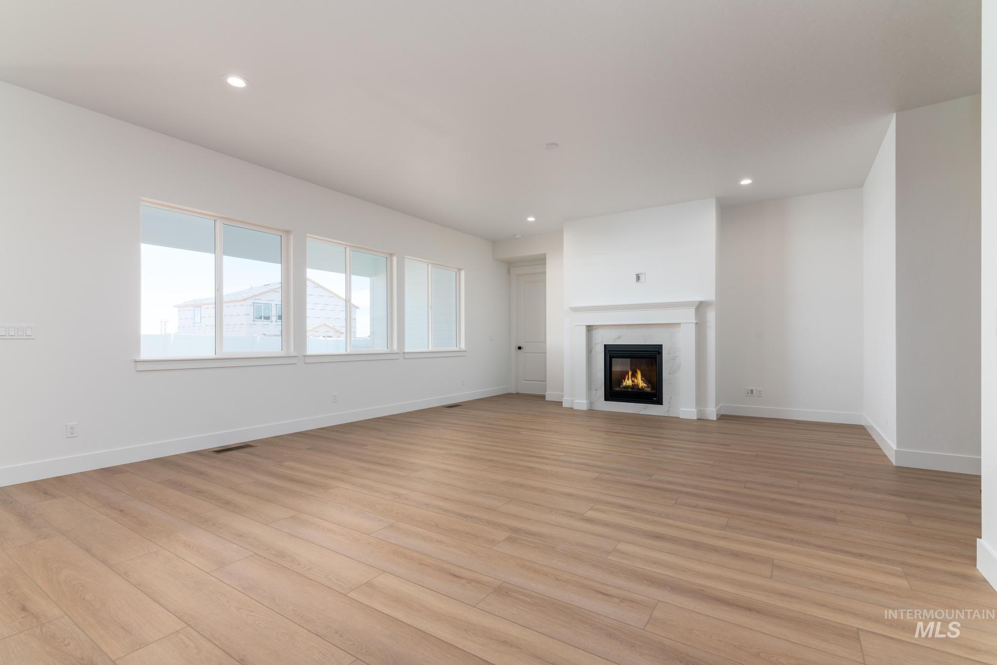 15216 Steel Cloud Avenue Caldwell, ID 83607 - Photo 5 of 32 Unfurnished living room featuring recessed lighting, light wood-type flooring, and a glass covered fireplace