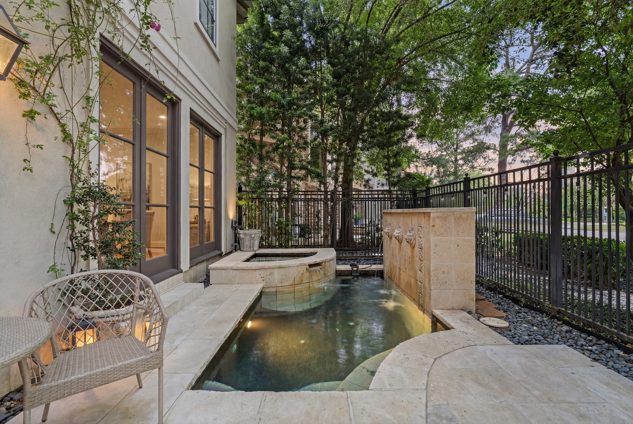 30 Hackberry Lane, Unit A Houston, TX 77027 - Photo 2 of 42 Secluded outdoor patio with cocktail-style pool and heated spa, surrounded by mature greenery and limestone decking—ideal for private relaxation or entertaining.
