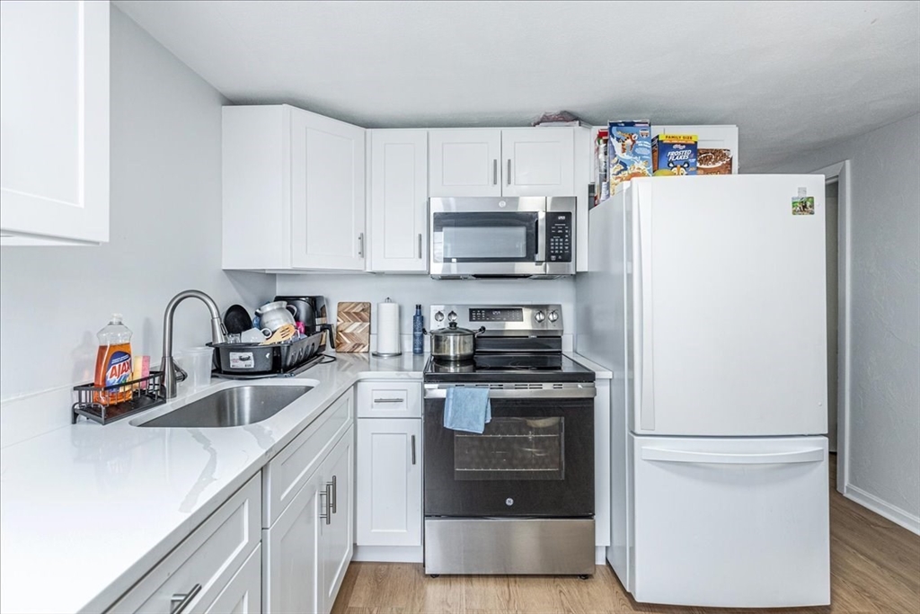 38 Warren Street Revere, MA 02151 - Photo 25 of 42 a kitchen with stainless steel appliances a refrigerator a sink and white cabinets