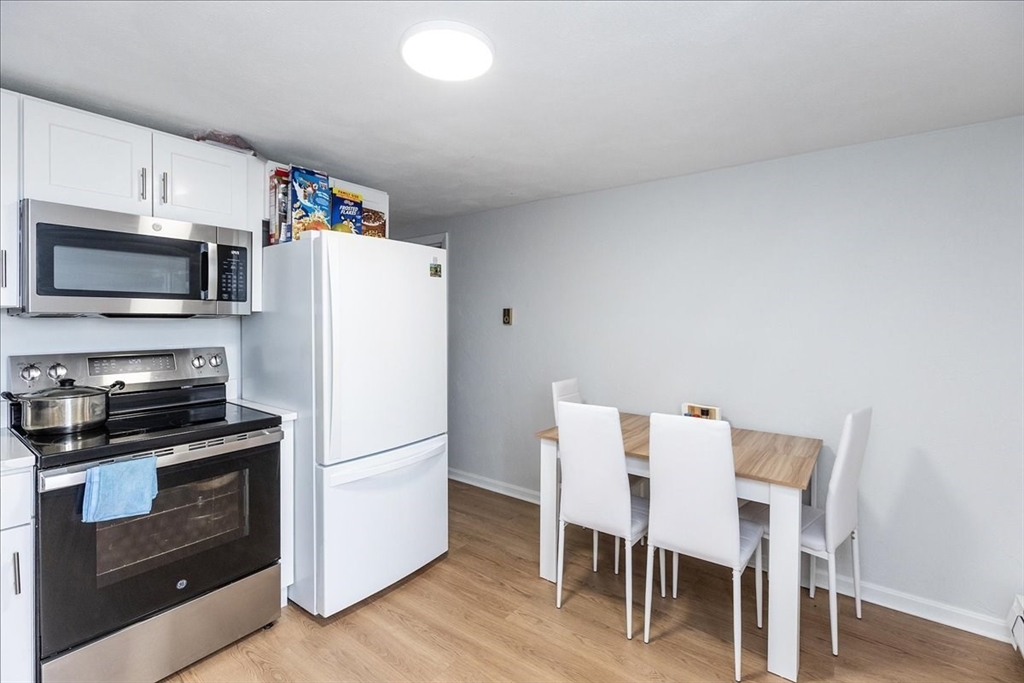 38 Warren Street Revere, MA 02151 - Photo 26 of 42 a white kitchen with wooden floor and stainless steel appliances