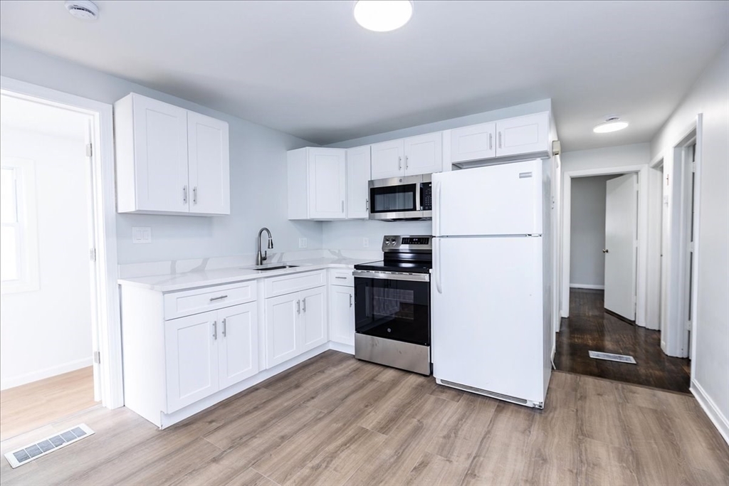 38 Warren Street Revere, MA 02151 - Photo 10 of 42 a kitchen with a refrigerator a stove top oven and white walls