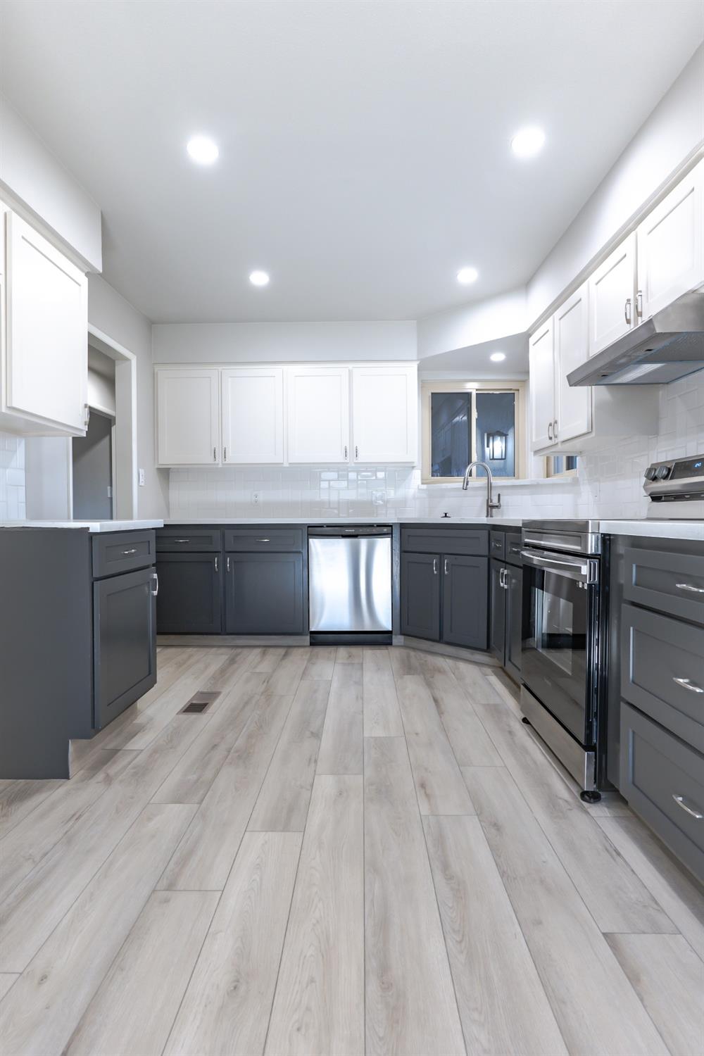 6587 North First Street Fresno, CA 93710 - Photo 14 of 51 a large kitchen with wooden floors and stainless steel appliances