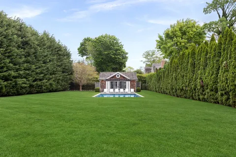 a view of a big house with a big yard and large trees