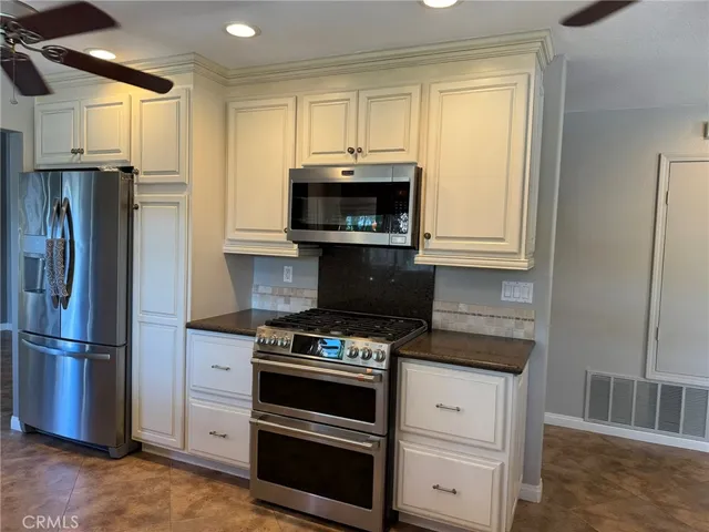 a kitchen with granite countertop a refrigerator stove and microwave