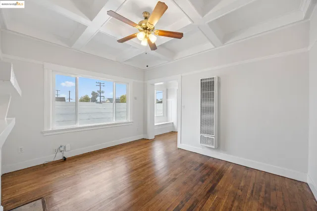 a view of an empty room with a window and wooden floor