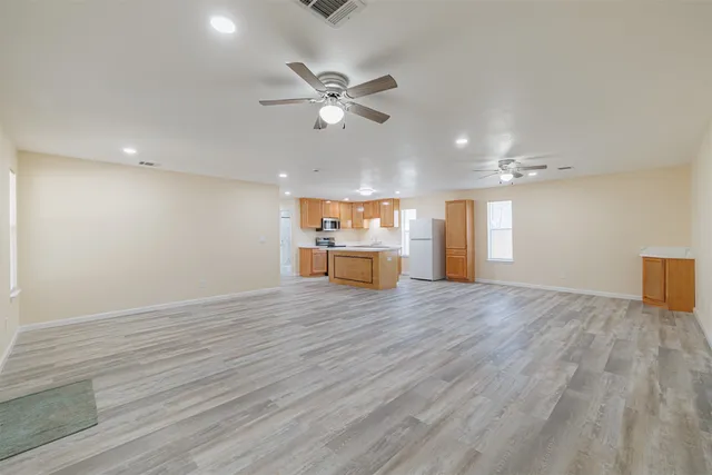 a view of an empty room with a window and wooden floor