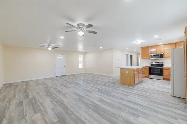 a view of kitchen and empty room with wooden floor