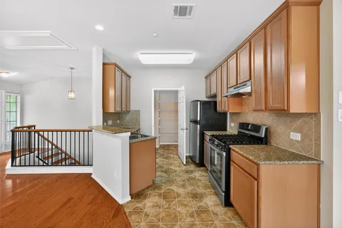 a kitchen with stainless steel appliances granite countertop a refrigerator oven a sink dishwasher and white cabinets with wooden floor