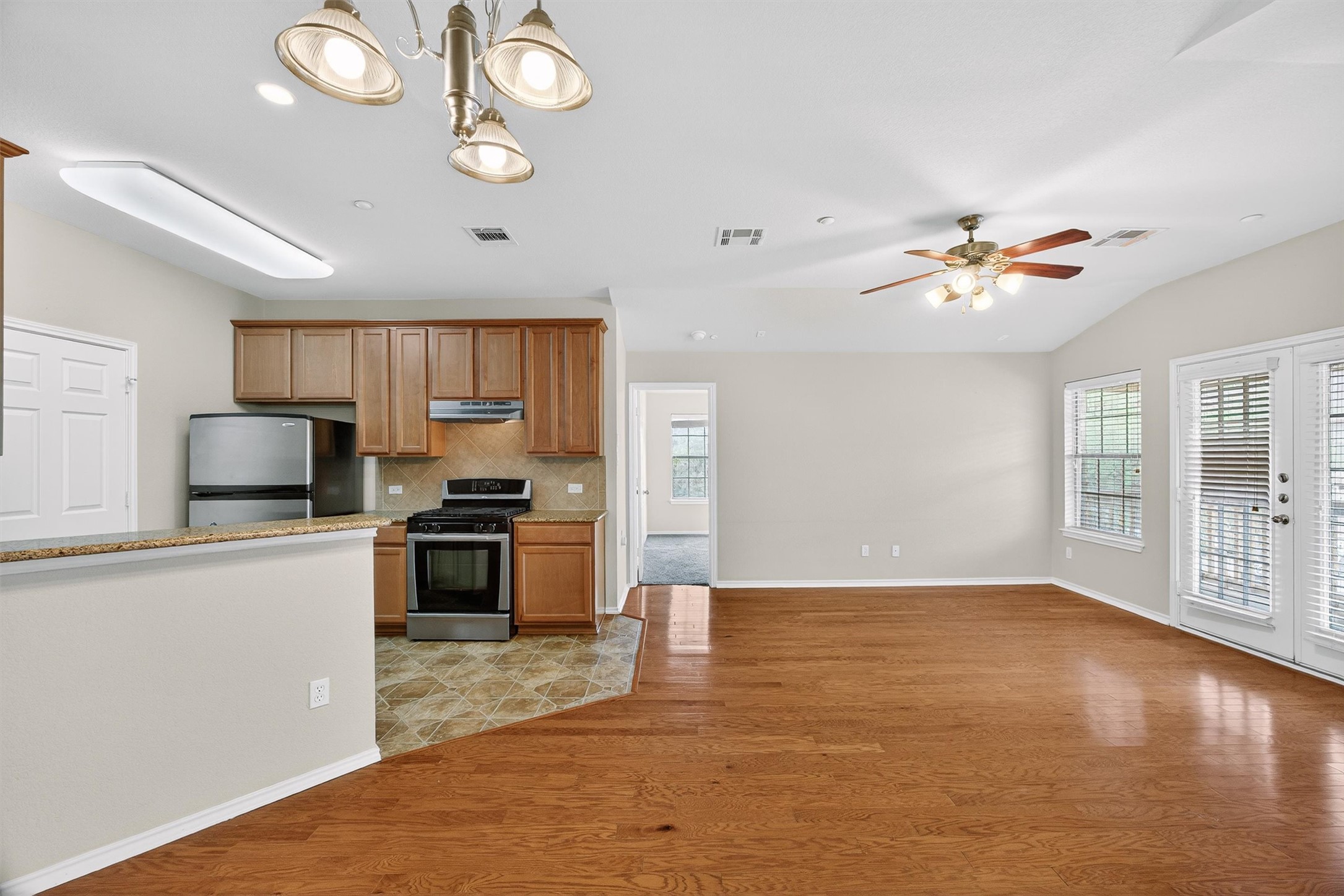 1310 West Parmer Lane, Unit 601 Austin, TX 78727 - Photo 23 of 40 a kitchen with kitchen island granite countertop a stove top oven a sink dishwasher a dining table and chairs with wooden floor