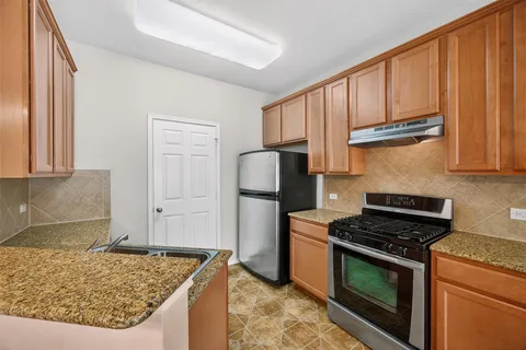 a kitchen with granite countertop wooden cabinets and stainless steel appliances