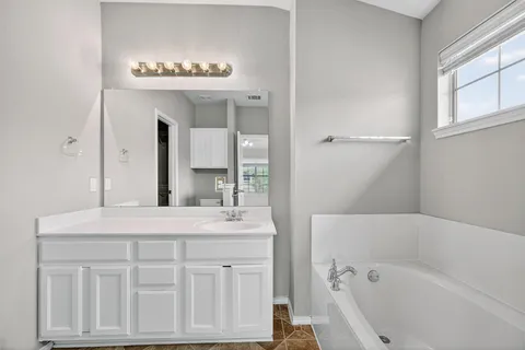 a bathroom with a tub sink shower and mirror