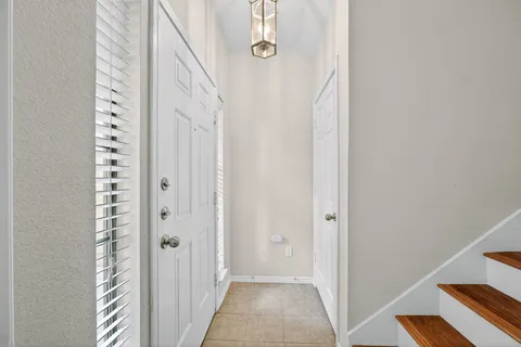a view of an empty room with chandelier fan and kitchen view