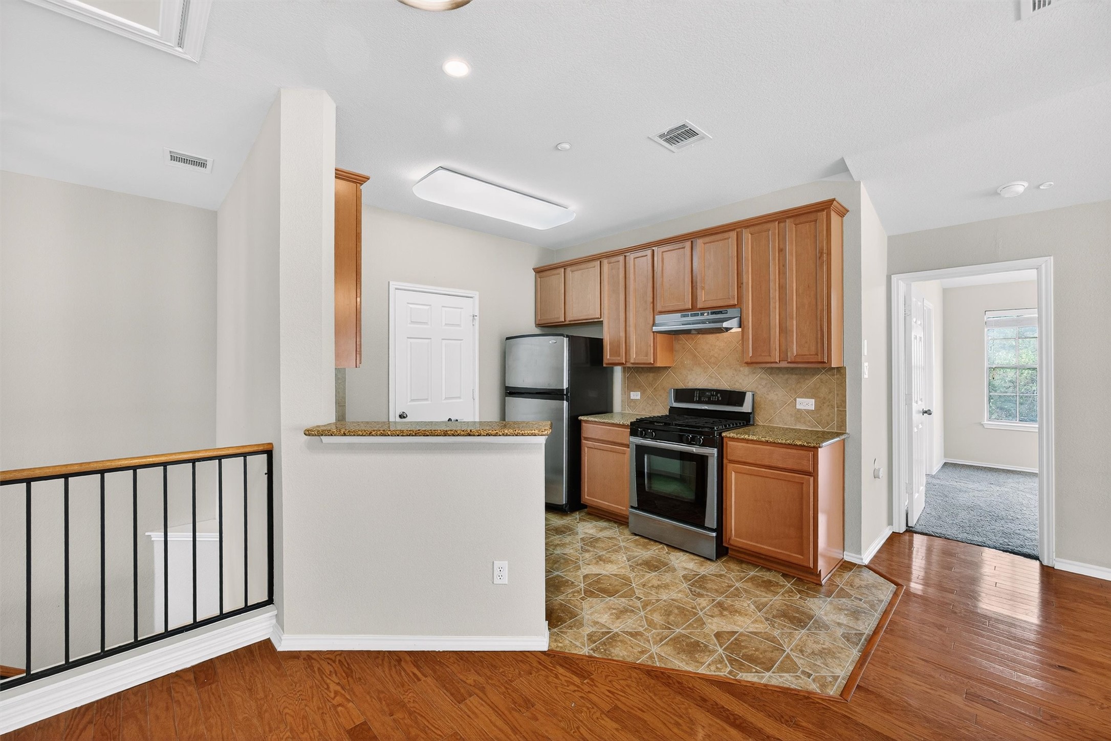 1310 West Parmer Lane, Unit 601 Austin, TX 78727 - Photo 8 of 40 a kitchen with stainless steel appliances granite countertop a refrigerator oven a sink dishwasher and white cabinets with wooden floor