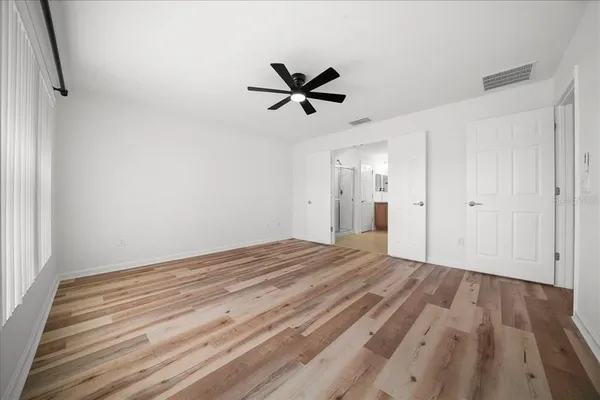 a view of empty room with wooden floor and ceiling fan