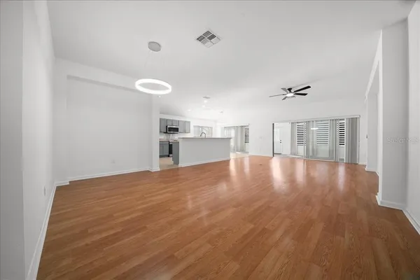 a view of empty room with wooden floor and kitchen view
