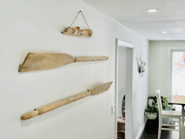 a white kitchen with a white stove a dining table and chairs with wooden floor