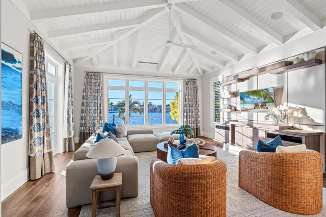 a living room with furniture large windows and wooden floor