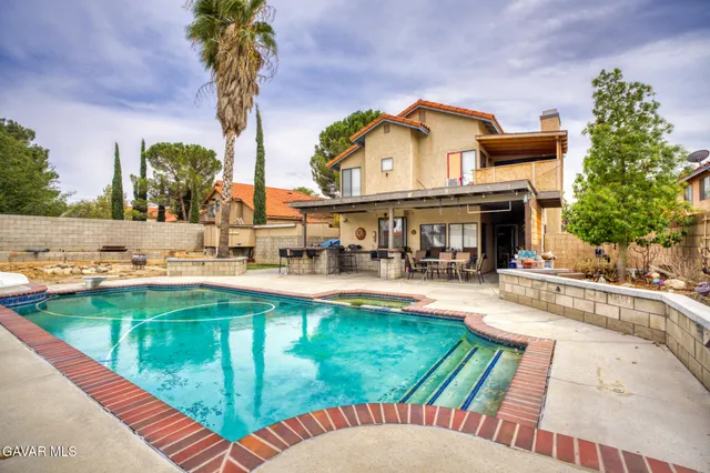 a view of a swimming pool with a patio and a yard with plants