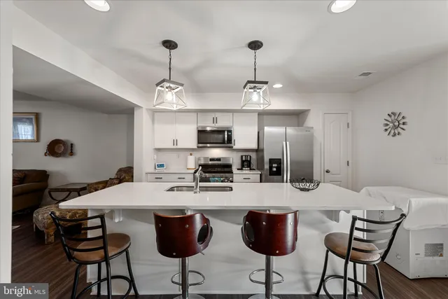 a kitchen with stainless steel appliances kitchen island granite countertop a dining table chairs and a refrigerator