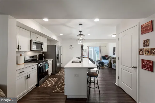 a kitchen with stainless steel appliances a stove top oven a sink dishwasher and a refrigerator with wooden floor