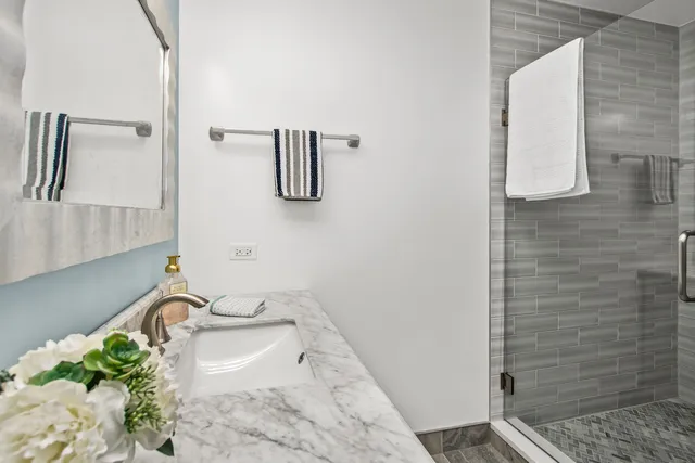 a bathroom with a granite countertop sink a mirror and shower