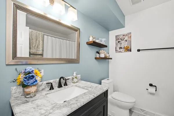 a bathroom with a granite countertop toilet sink and mirror