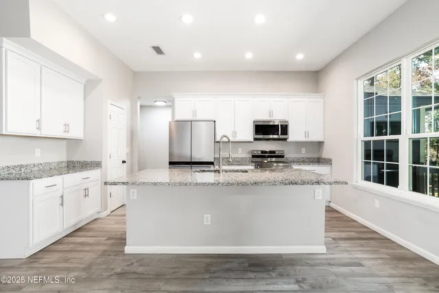 a view of kitchen with granite countertop a stove top oven a sink and white cabinets