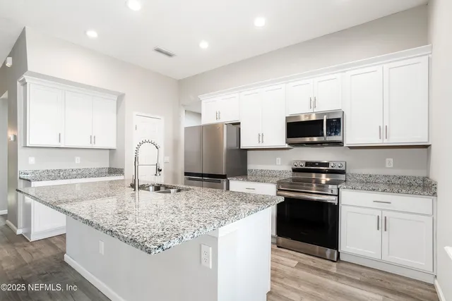 a large kitchen with stainless steel appliances granite countertop a stove a sink and a microwave