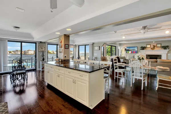 a kitchen with stainless steel appliances kitchen island granite countertop a stove a sink a refrigerator and white cabinets with wooden floor
