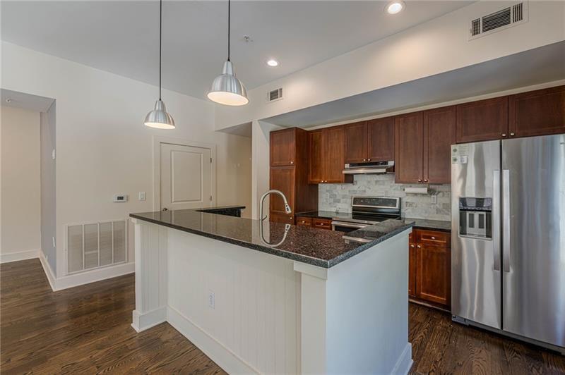 925 Garrett Street, Unit 215 Atlanta, GA 30316 - Photo 6 of 23 a kitchen with granite countertop stainless steel appliances a sink cabinets and wooden floor
