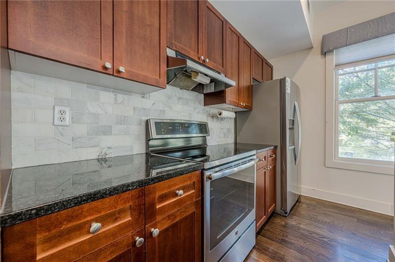 925 Garrett Street, Unit 215 Atlanta, GA 30316 - Photo 7 of 23 a kitchen with stainless steel appliances granite countertop a sink a stove a refrigerator cabinets and wooden floor
