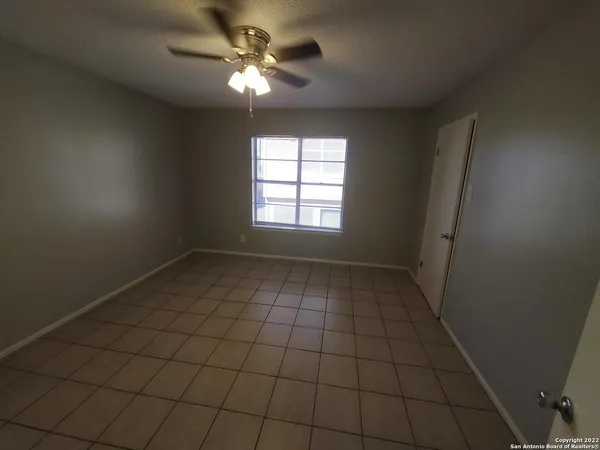 an empty room with windows and fan