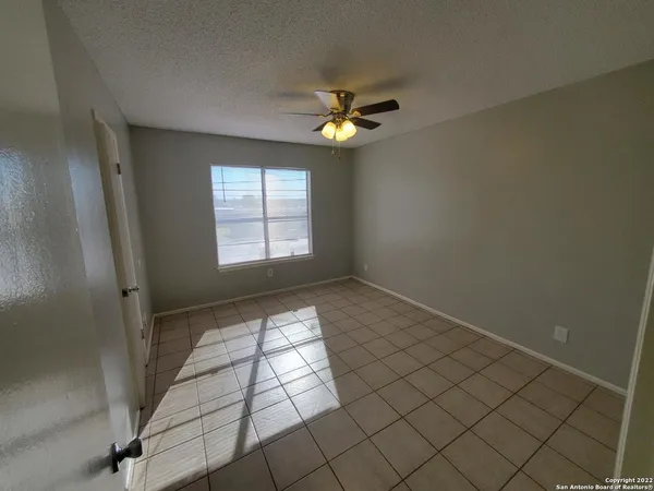 an empty room with windows and fan