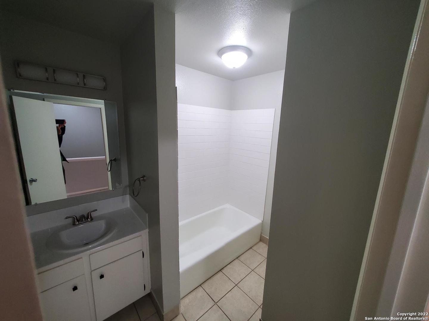 911 Y Vance Jackson Road San Antonio, TX 78201 - Photo 10 of 18 a bathroom with a bathtub a mirror a vanity and vanity