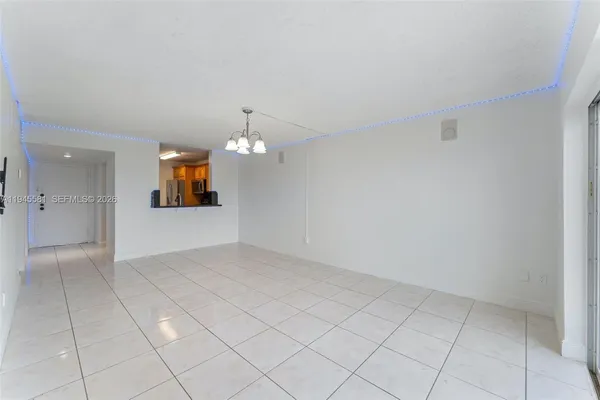 an empty room with chandelier fan and window