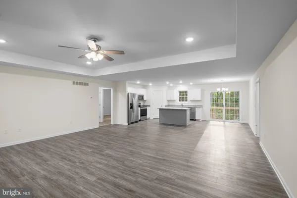 a view of an empty room with a kitchen and a window