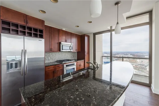 a kitchen with stainless steel appliances granite countertop a refrigerator a stove and a wooden floors