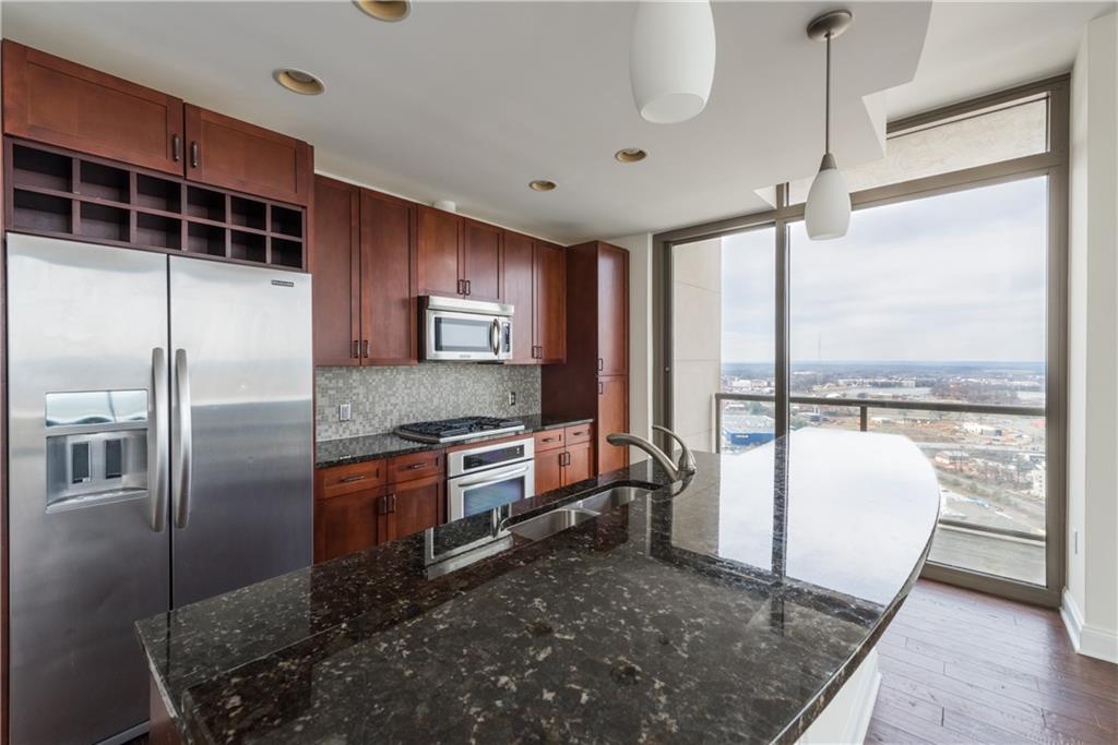 270 17th Street Northwest, Unit 3110 Atlanta, GA 30363 - Photo 6 of 23 a kitchen with stainless steel appliances granite countertop a refrigerator a stove and a wooden floors