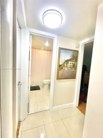 a view of a hallway with wooden floor and a bathroom