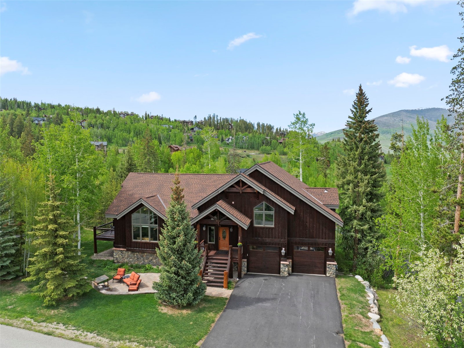 736 Wild Rose Road Silverthorne, CO 80498 - Photo 1 of 49 Chalet / cabin with asphalt driveway, stone siding, an attached garage, and a forest view