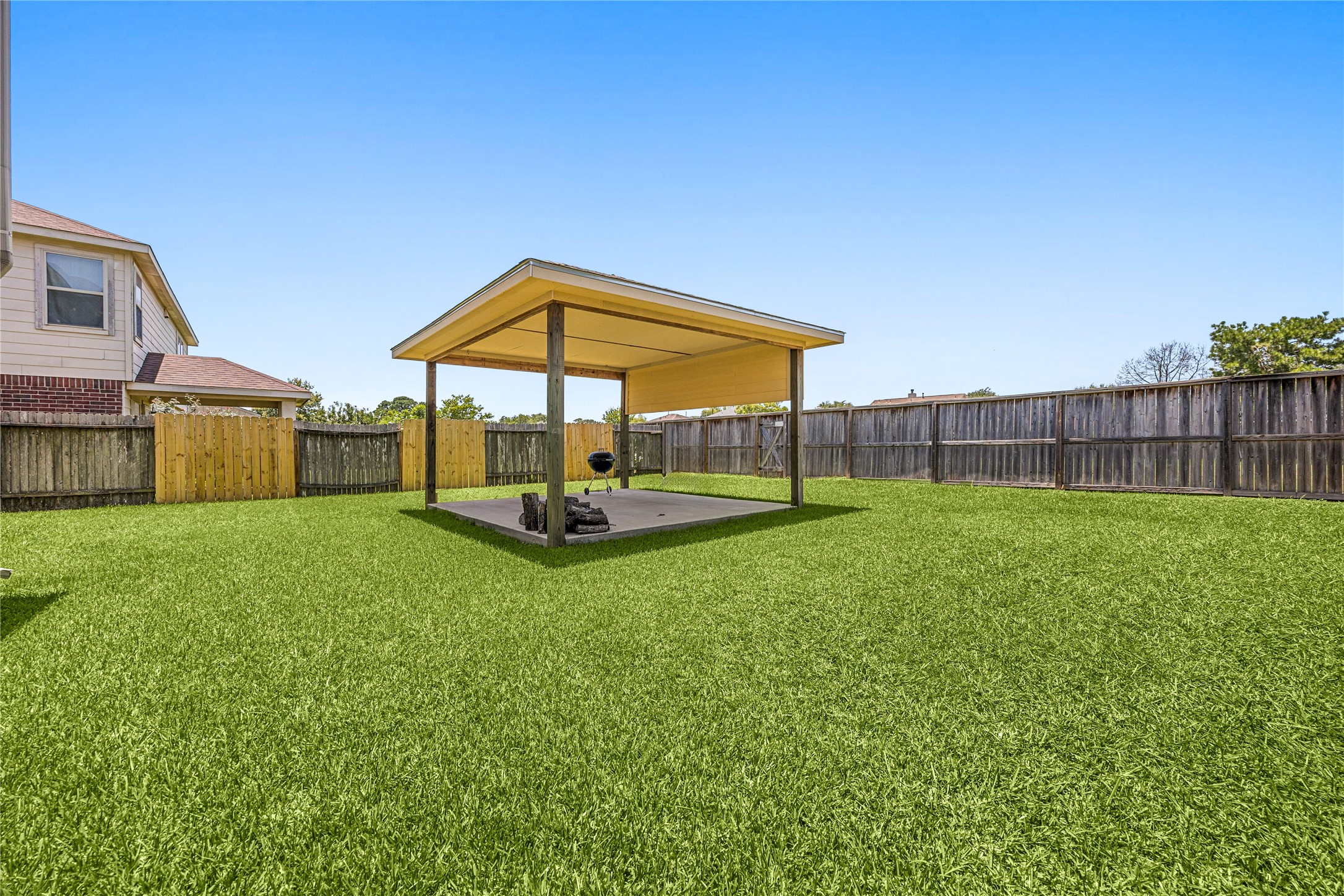 13407 Spring Line Court Houston, TX 77086 - Photo 25 of 29 This expansive backyard view highlights a premium, detached covered patio that serves as the ultimate focal point for outdoor living and entertainment. Set against a lush, sprawling green lawn with the incredible advantage of no rear neighbors, this private oasis offers unobstructed skyline views and total tranquility.