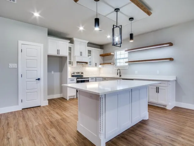 a kitchen with kitchen island a sink stainless steel appliances and wooden floor