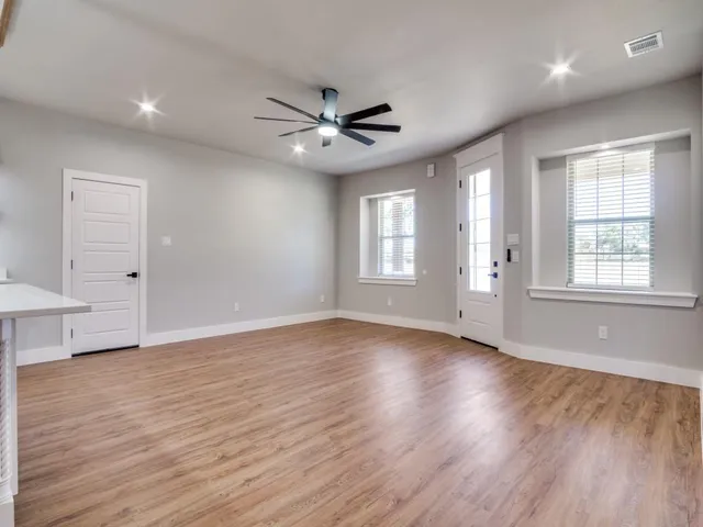 a view of an empty room with wooden floor and a window